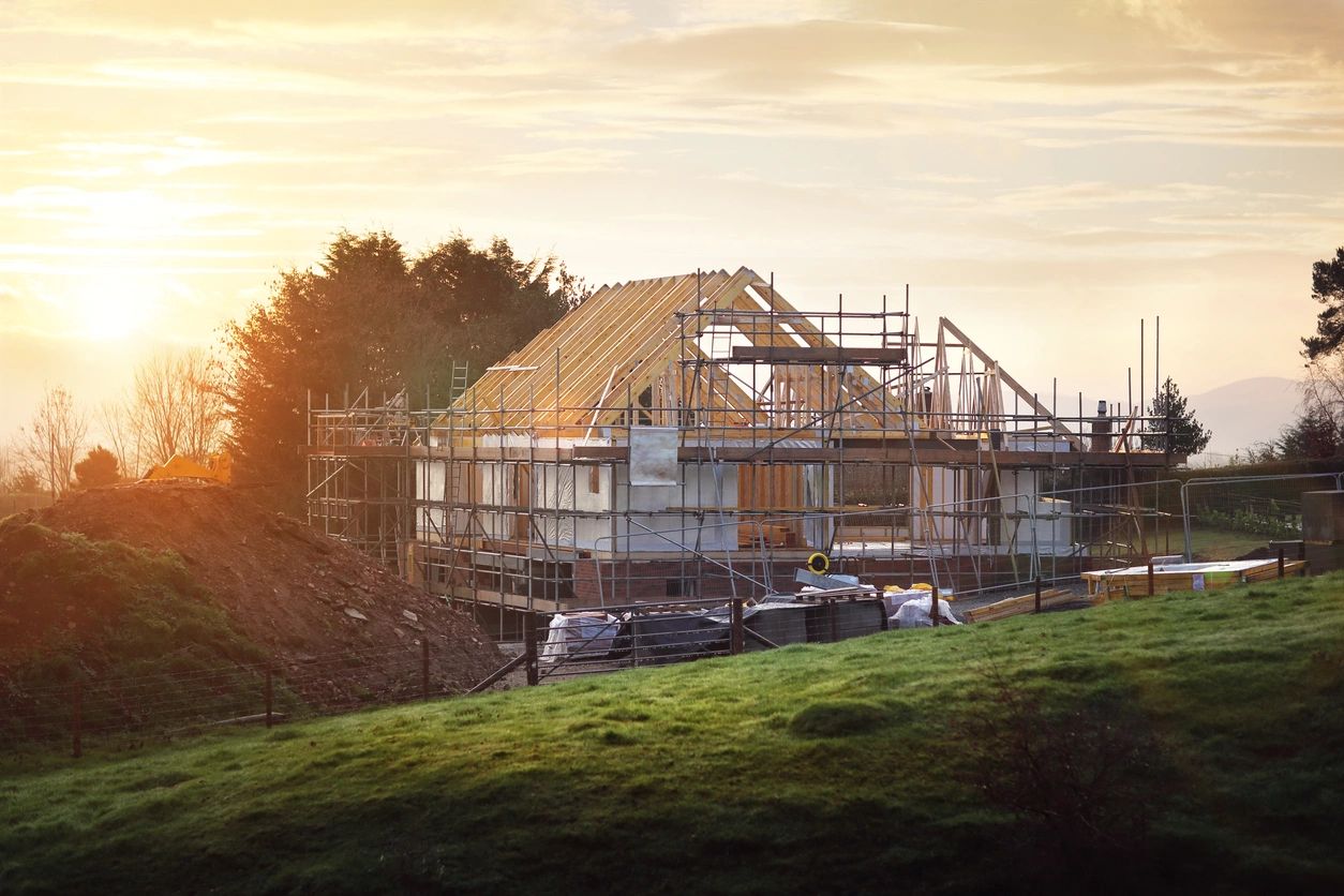 A house under construction at sunset with scaffolding around it.