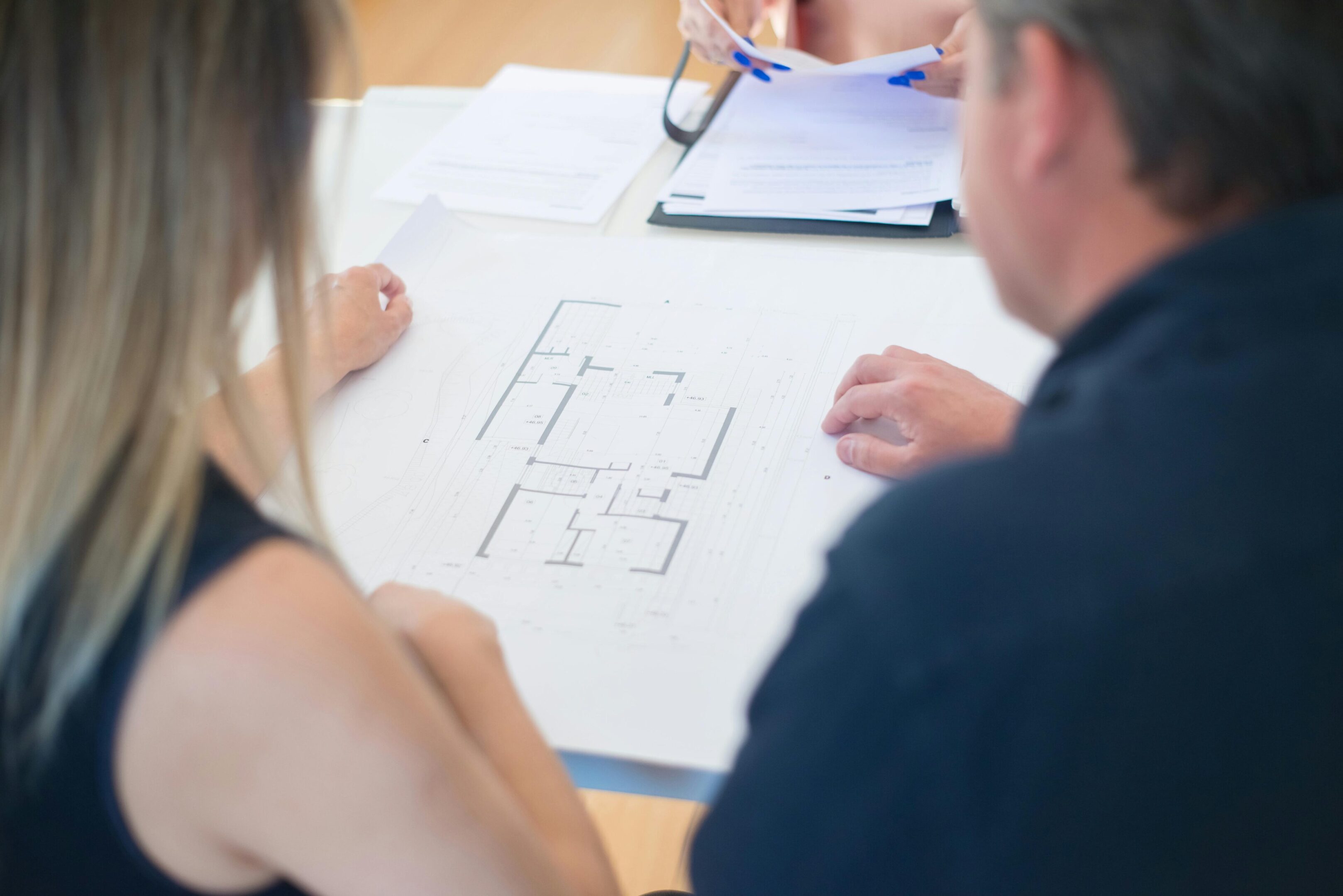 Two people reviewing architectural floor plans at a table.
